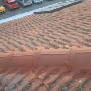 גג רעפים חום עם מכוניות חונות ברקע