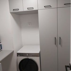 מכונת כביסה בחדר כביסה עם ארונות אפורים