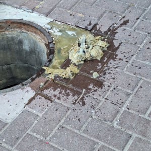 פתח ביוב עם פסולת על המדרכה