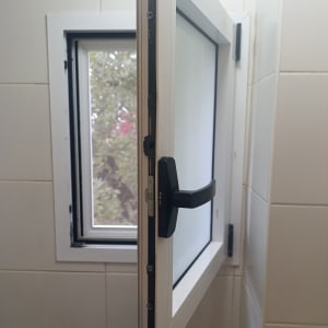 חלון אלומיניום פתוח עם ידית שחורה