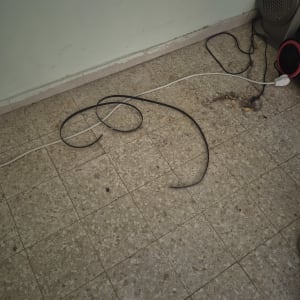 רצועת הנעה שחורה וכבל חשמל על הרצפה במהלך תיקון מכשיר חשמלי