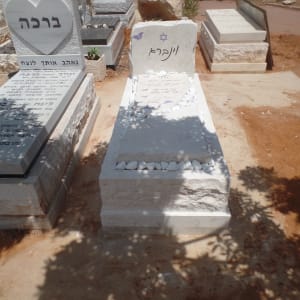 מצבות בבית קברות עם כיתוב בעברית ואבנים לבנות