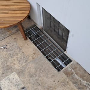 סורג מתכת על רצפה ליד קיר לבן