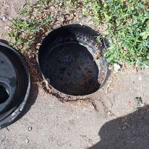 בור פתוח עם מכסה לידו וכלי עבודה על הקרקע