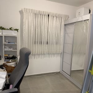 חדר עם וילון, כיסא ומדף עם צמחים