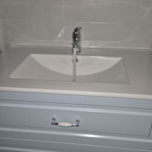 ברז מים זורם בכיור לבן עם ארון תחתון