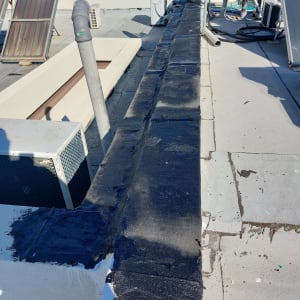 איטום גג עם חומר שחור על קיר בטון