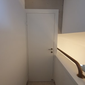 דלת לבנה במסדרון צר עם מעקה מתכת