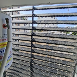 רשת יונים מותקנת על מרפסת עם נוף לבניינים