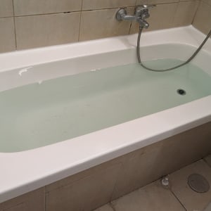 אמבטיה מלאה במים עם ברז ומקלחת יד