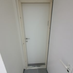 דלת לבנה עם ידית כסופה בחדר קטן