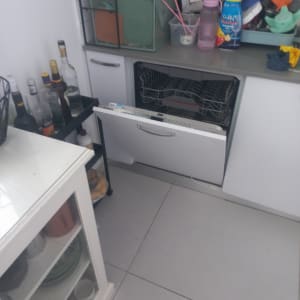 מטבח עם מדיח כלים פתוח וכלים על השיש