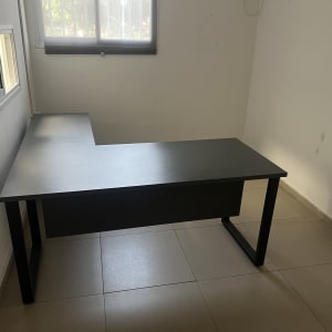 שולחן עבודה שחור ריק בחדר ריק עם חלון