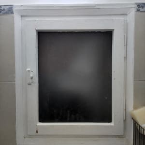 חלון זכוכית מט במרכז מסגרת עץ לבנה