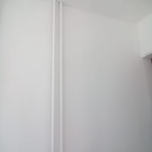 קיר צבוע בלבן עם צינורות אנכיים