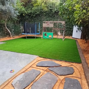 דשא סינתטי, עצים, צינור השקיה, שביל אבנים