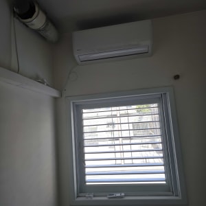 מזגן מותקן על קיר מעל חלון עם תריסים