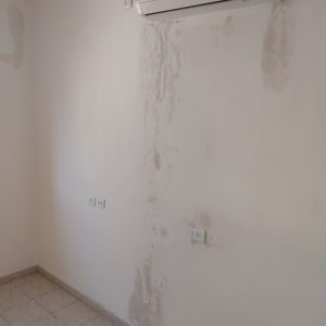 קיר עם סימני תיקון צבע מתחת למזגן