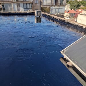 גג אטום בזפת שחורה עם קולטי שמש