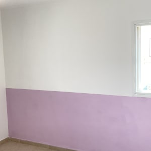 קיר צבוע בחצי סגול וחצי לבן עם חלון