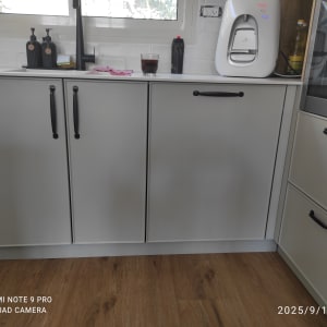 ארונות מטבח עם ידיות שחורות ומכשיר חשמלי על השיש