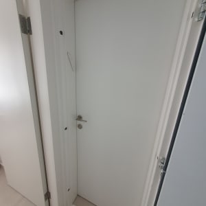 דלת לבנה עם ידית מתכת ומסגרת לבנה