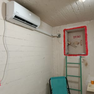 מזגן מותקן על קיר בחדר עם סולם וכיור