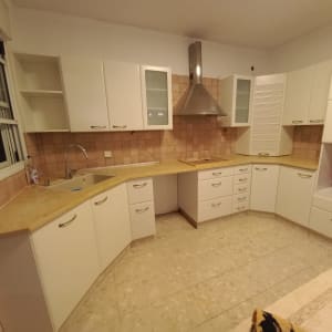 מטבח עם ארונות לבנים וכיור נירוסטה