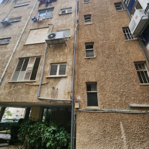 בניין עם מזגנים וצינורות חיצוניים על הקיר