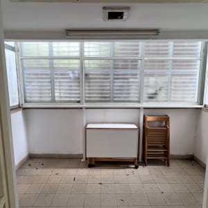 חדר ריק עם חלונות, ארון קטן וכיסא מתקפל