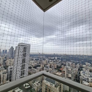 רשת יונים מותקנת במרפסת עם נוף עירוני