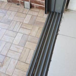 מסילה מלוכלכת ליד דלת הזזה על רצפה מרוצפת