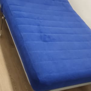 מיטה עם מזרן כחול על רצפת עץ