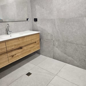 כיור עם ברז, אריחים אפורים וניקוז ברצפה