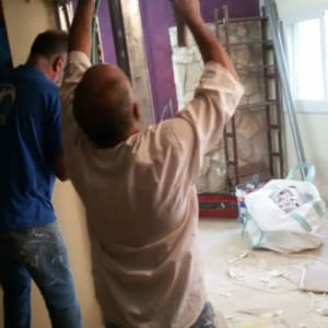 שני אנשים עובדים עם פטיש ומסור במהלך שיפוץ