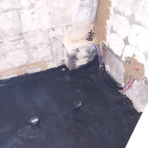 קירות מטויחים, צנרת חשופה, רצפה עם חומר איטום שחור