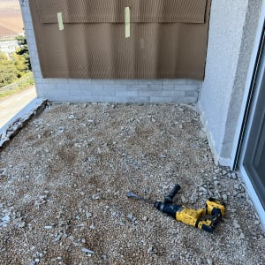 כלי עבודה על רצפת חצץ ליד קיר אטום בנייר