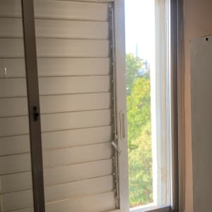 חלון זכוכית פתוח עם תריסים לבנים