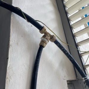 צינור שחור עם מחבר מתכת על קיר לבן