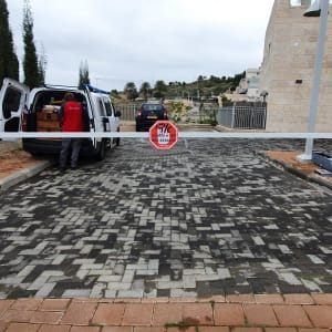 שער חשמלי עם מחסום לבן ומתקין ליד רכב מסחרי