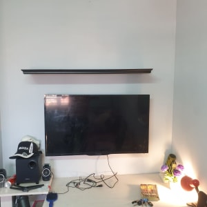 מדף תלוי מעל טלוויזיה עם חוטים על שולחן
