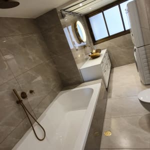 חדר אמבטיה עם אמבטיה, כיור ומראה עגולה