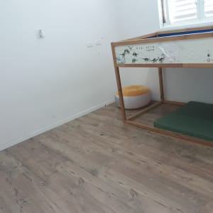 מיטה מוגבהת עם מזרן ירוק וכרית כתומה