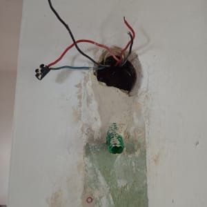 חוטי חשמל חשופים יוצאים מקיר עם צינור ירוק