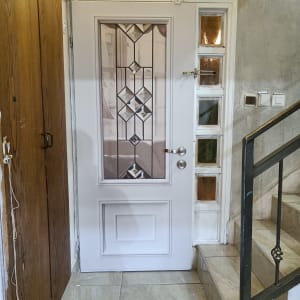 דלת לבנה עם זכוכית מעוצבת ומנעול כסוף
