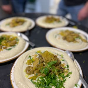 צלחות חומוס עם פטריות ועשבי תיבול מוגשות על שולחן