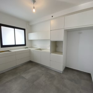 מטבח עם ארונות לבנים ומשטח עבודה