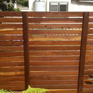 גדר עץ חומה עם צמחים ירוקים מלפנים