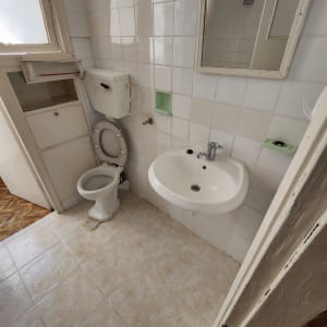 כיור ושירותים בחדר אמבטיה עם אריחים לבנים