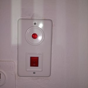 מתג חשמלי עם נורית חיווי אדומה על קיר לבן